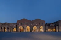 Beymen Tersane by OMA, the brick shipyard halls lit through their arches at dusk