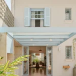 BF2 House by Peninsula Arquitetura, cream facade with light blue shutters and steel pergola