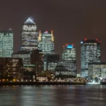 Canary Wharf skyline at night across the River Thames, with illuminated office towers including the Citi tower