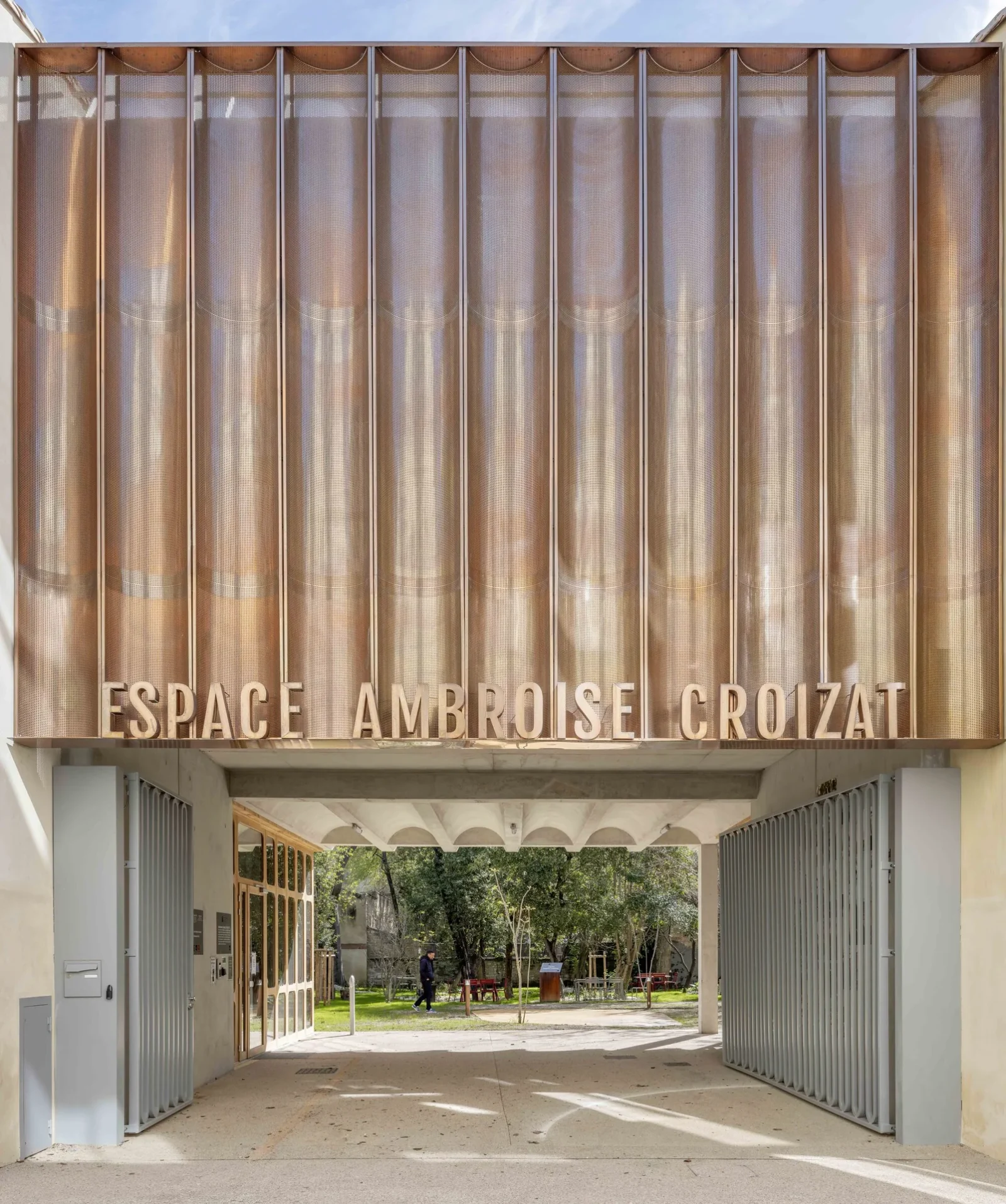 The street porch and copper sign of Espace Ambroise Croizat by TAUTEM Architecture