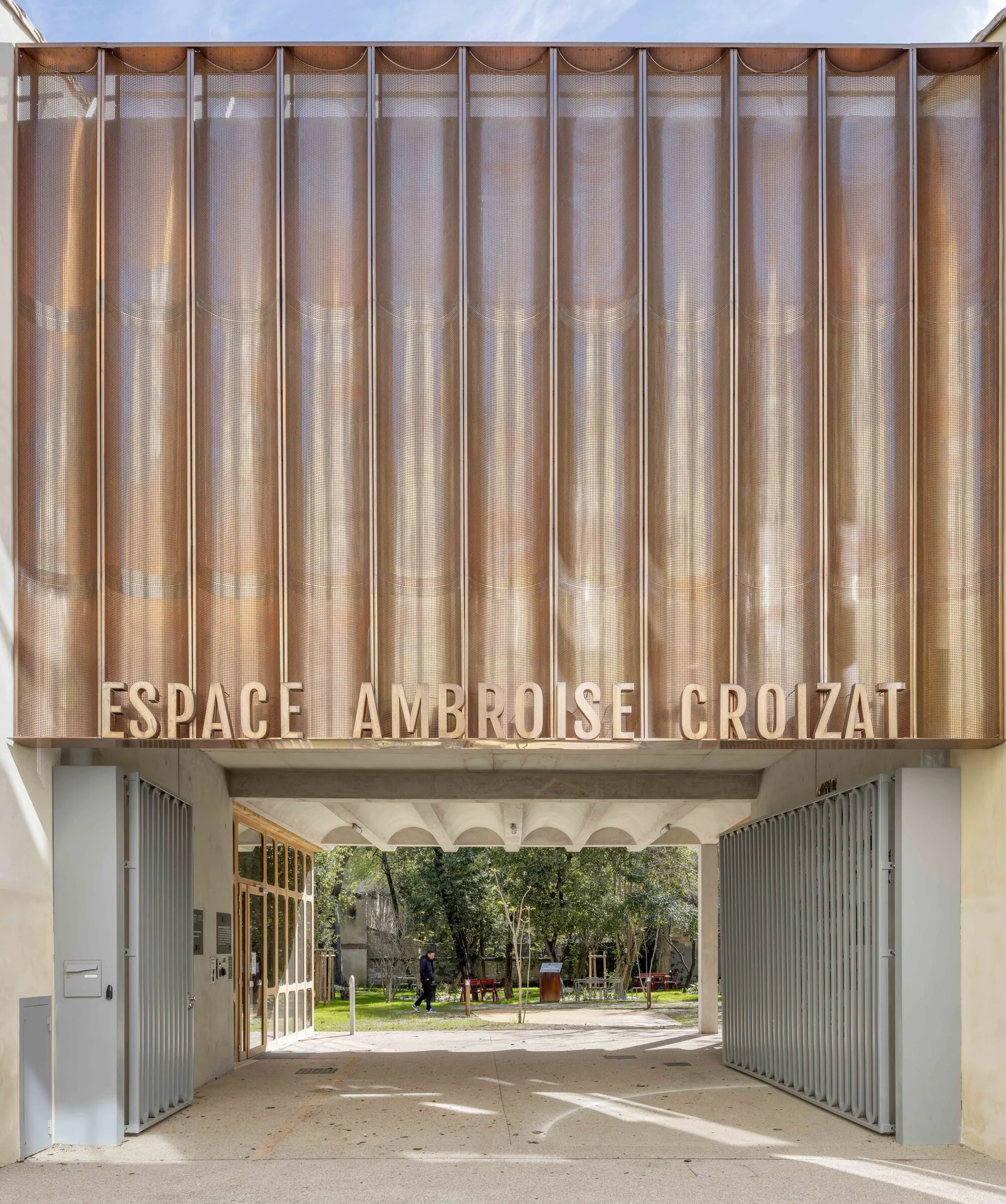 The street porch and copper sign of Espace Ambroise Croizat by TAUTEM Architecture