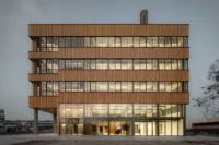 Timber-clad floors and terraces of Ferro Offices by GROUP A lit at dusk