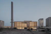 Ferro Offices by GROUP A and the harbour chimney at dusk, city towers beyond