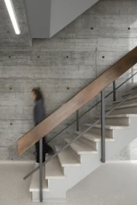The restored natural stone staircase and wooden handrail at Ferro Offices