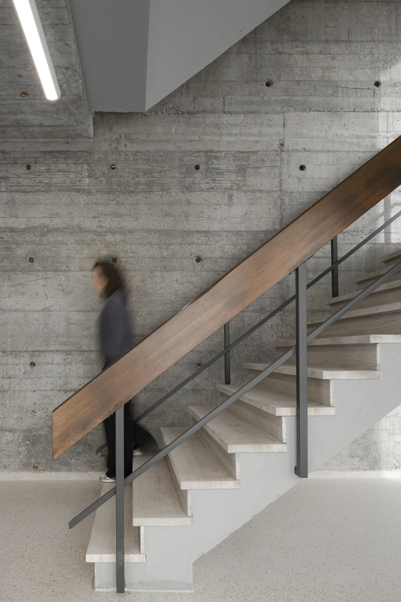 The restored natural stone staircase and wooden handrail at Ferro Offices