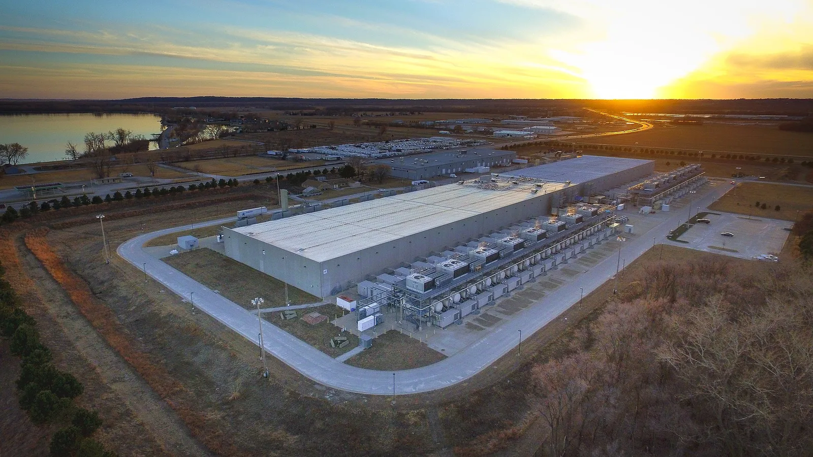 Aerial view of Google's Council Bluffs data centre in Iowa, a long windowless shed lined with cooling units at sunset