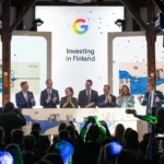 Officials clap on stage under a screen reading 'Investing in Finland' with the Google logo, confetti falling