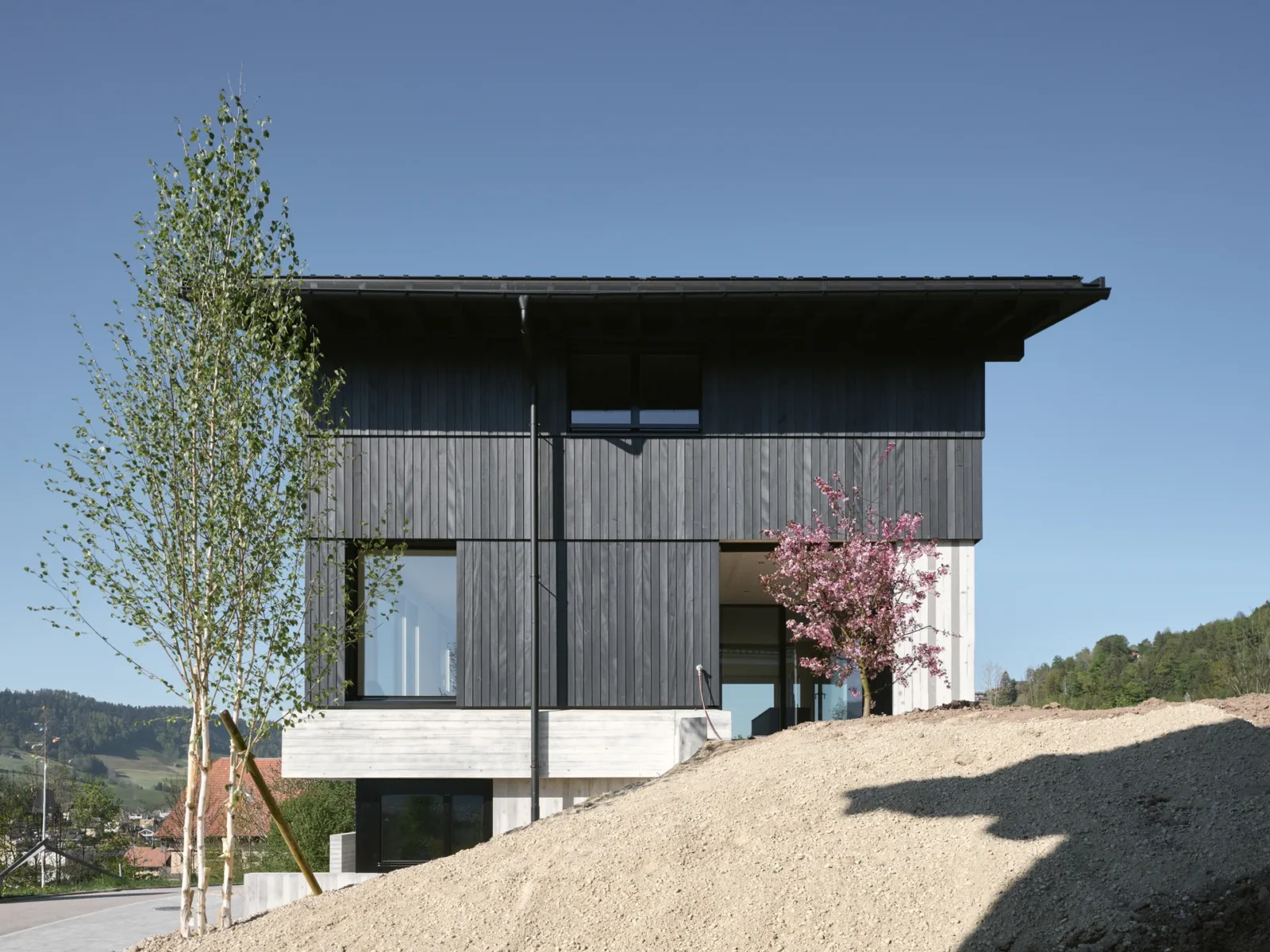 House on Concrete Walls by dolmus Architekten, timber volume resting on its concrete base