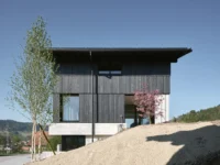 House on Concrete Walls by dolmus Architekten, timber volume resting on its concrete base