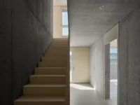 Timber stair rising through the concrete base of House on Concrete Walls