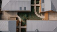 Aerial view of a low building whose separate wings wrap a planted central courtyard