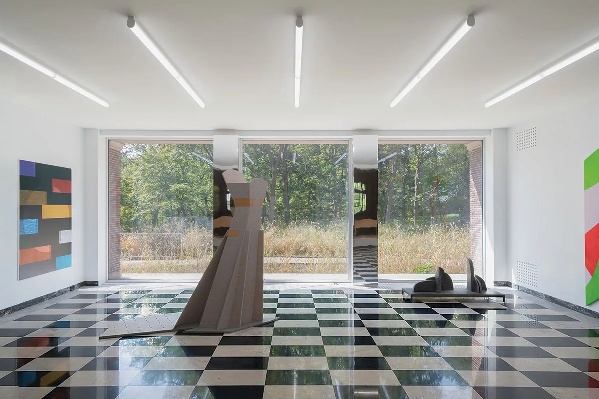 Gallery room with checkerboard floor, floor-to-ceiling windows, and abstract sculptures and paintings