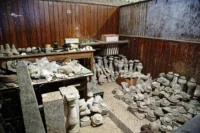 Room of an architectural salvage store with stone finials, balusters and carved fragments stacked on tables and the floor