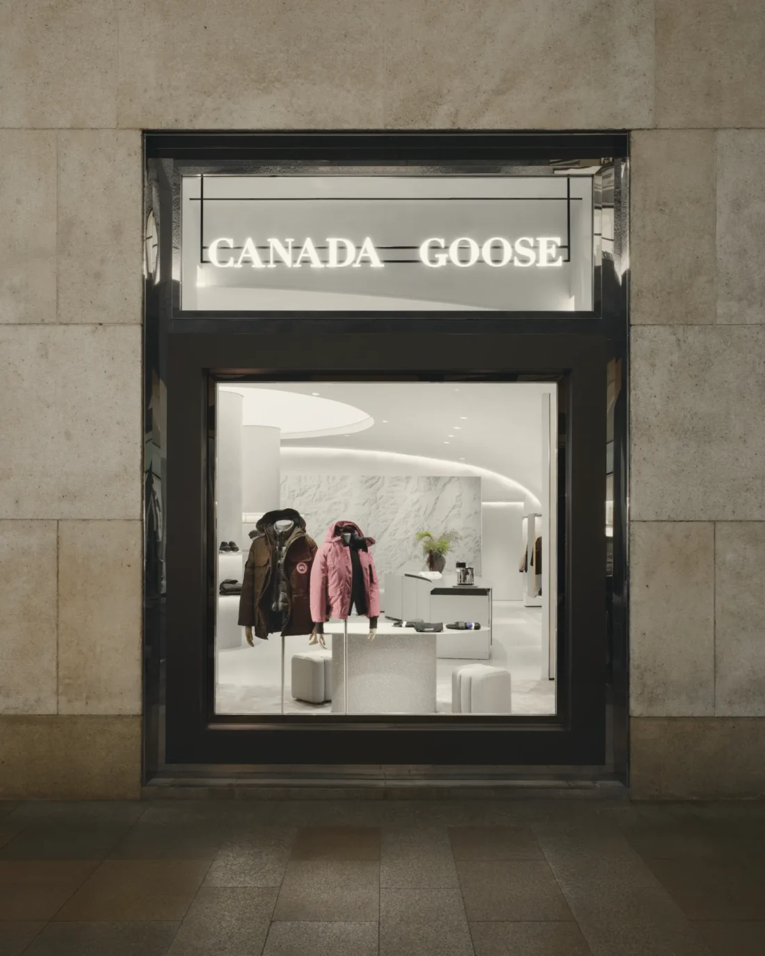 The shopfront seen from the street, framed like a vitrine into the lit interior