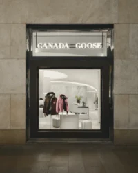 The shopfront seen from the street, framed like a vitrine into the lit interior