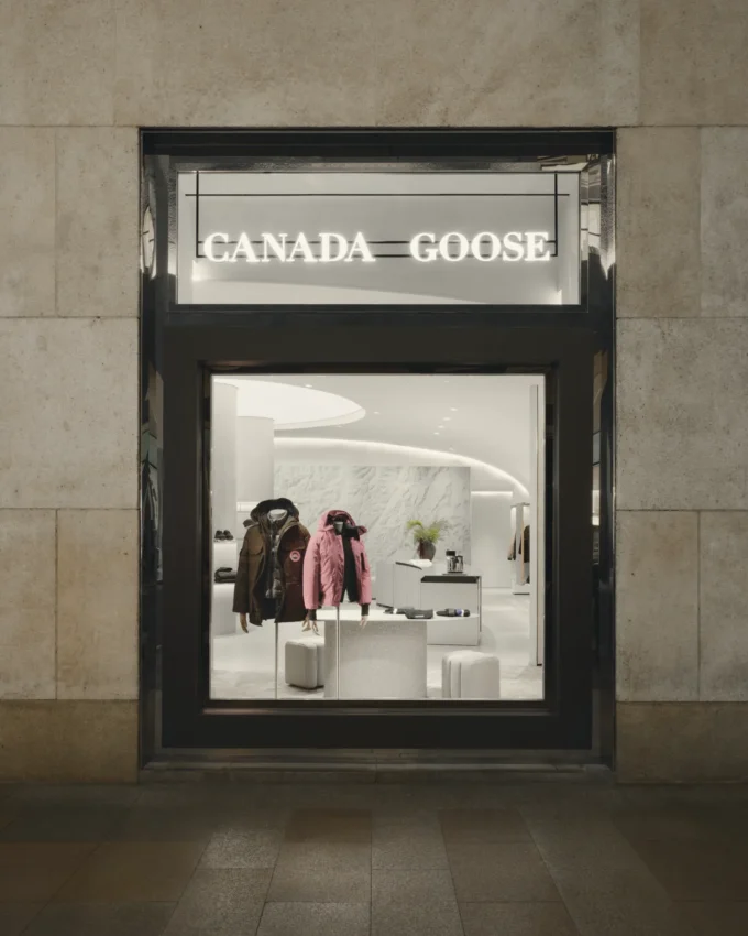 The shopfront seen from the street, framed like a vitrine into the lit interior