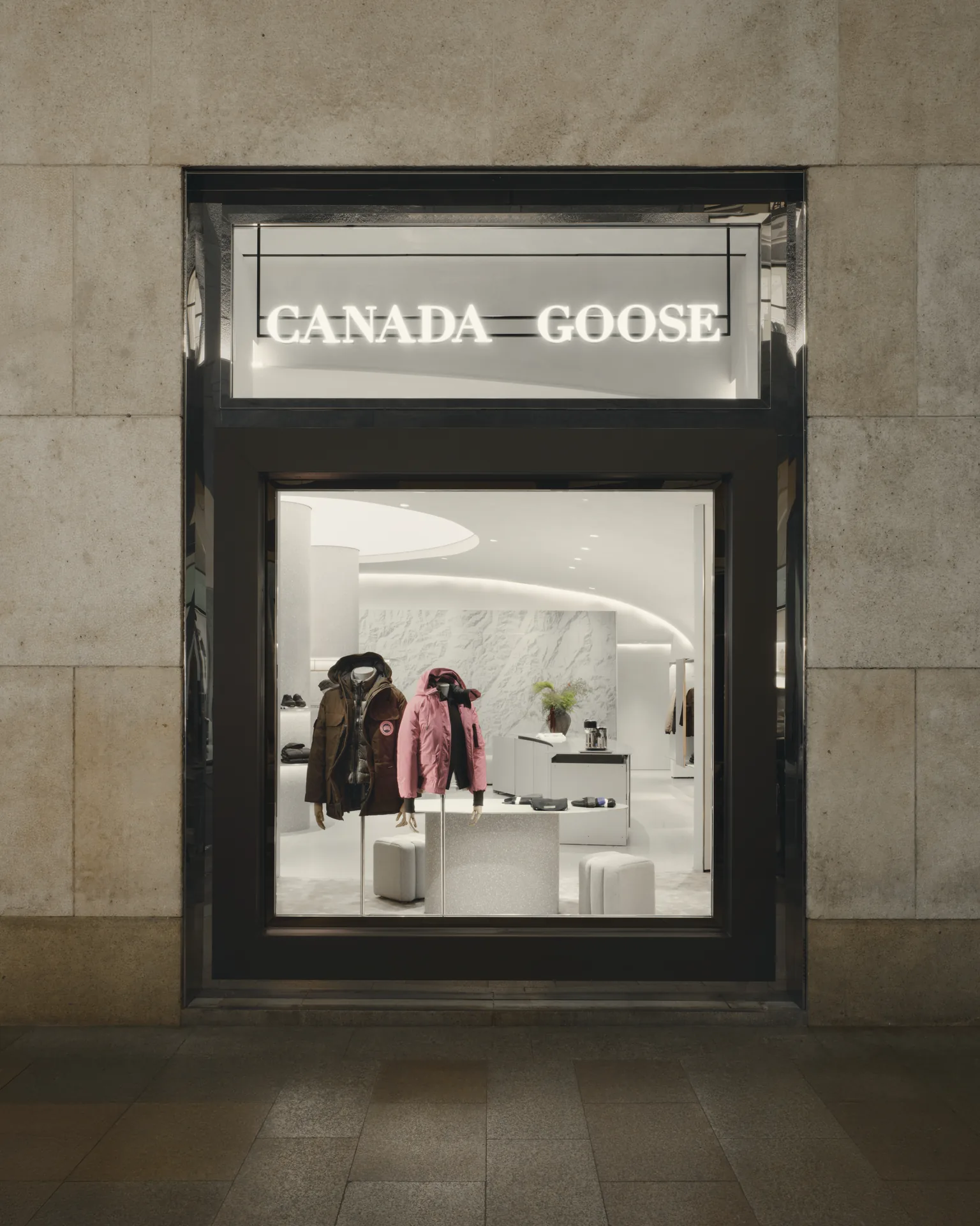 The shopfront seen from the street, framed like a vitrine into the lit interior