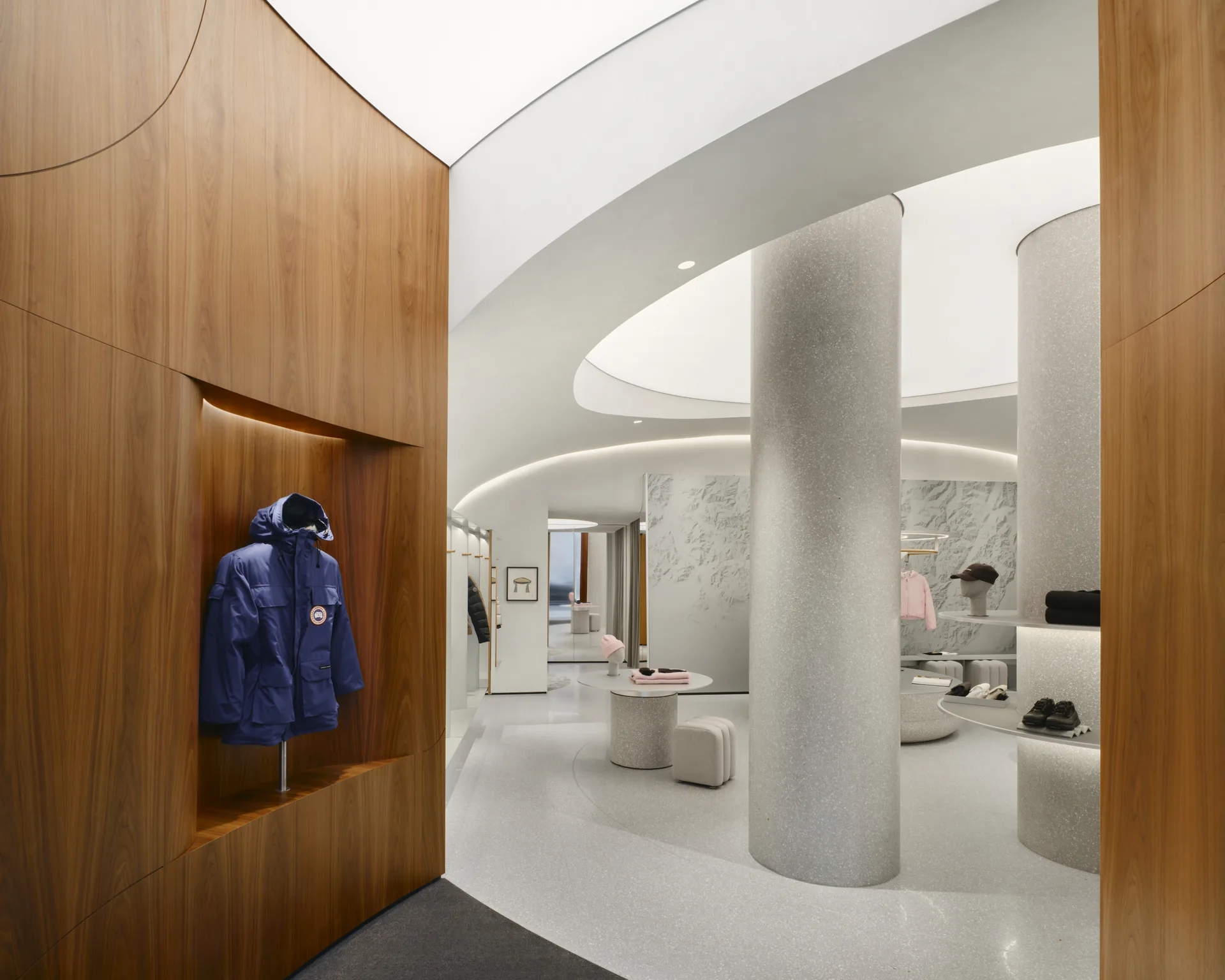 Walnut clad foyer wall with a parka displayed in a niche and the white room beyond