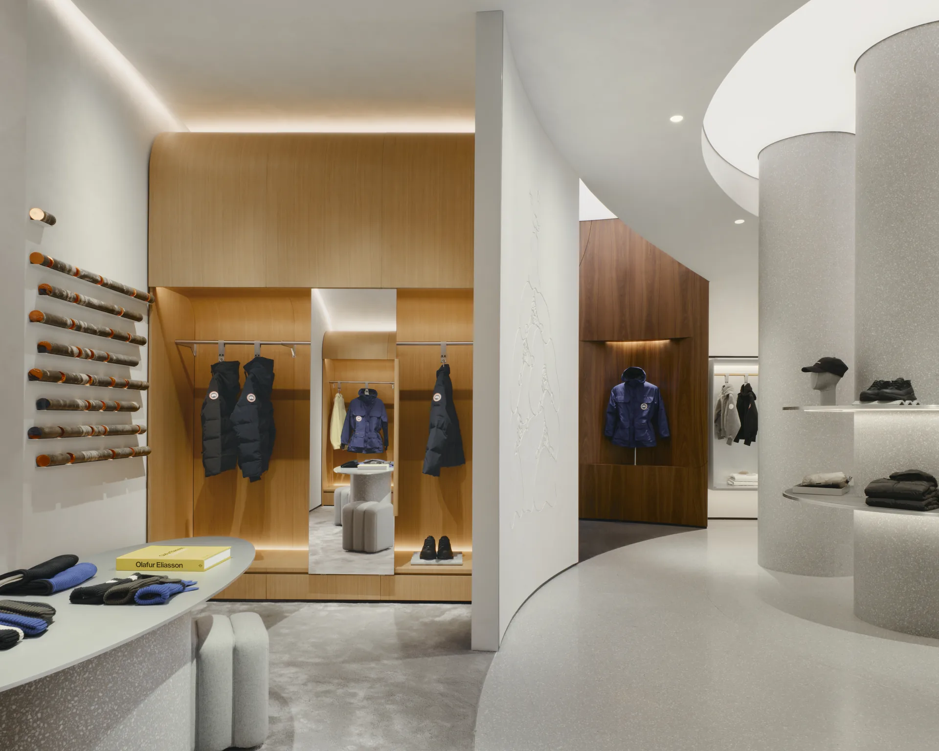 Walnut clad wall with accessory pegs and folded goods on open shelves