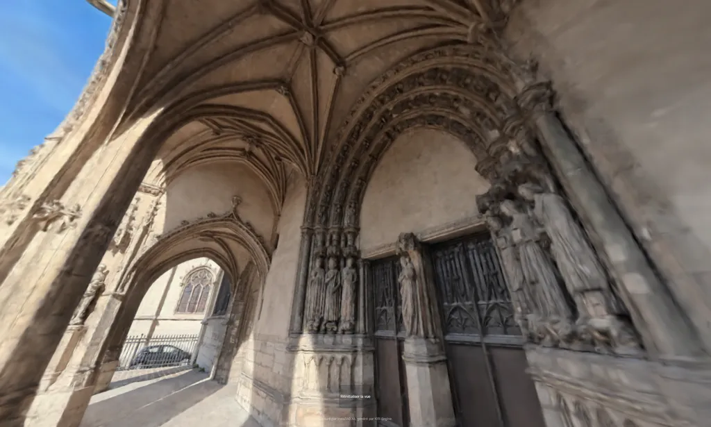 Gothic cathedral porch with ribbed vaulting, carved stone figures, and wooden doors