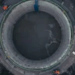 Aerial view of a large circular construction site with machinery and barriers