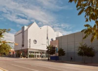 The building seen from the street corner with young trees along the pavement