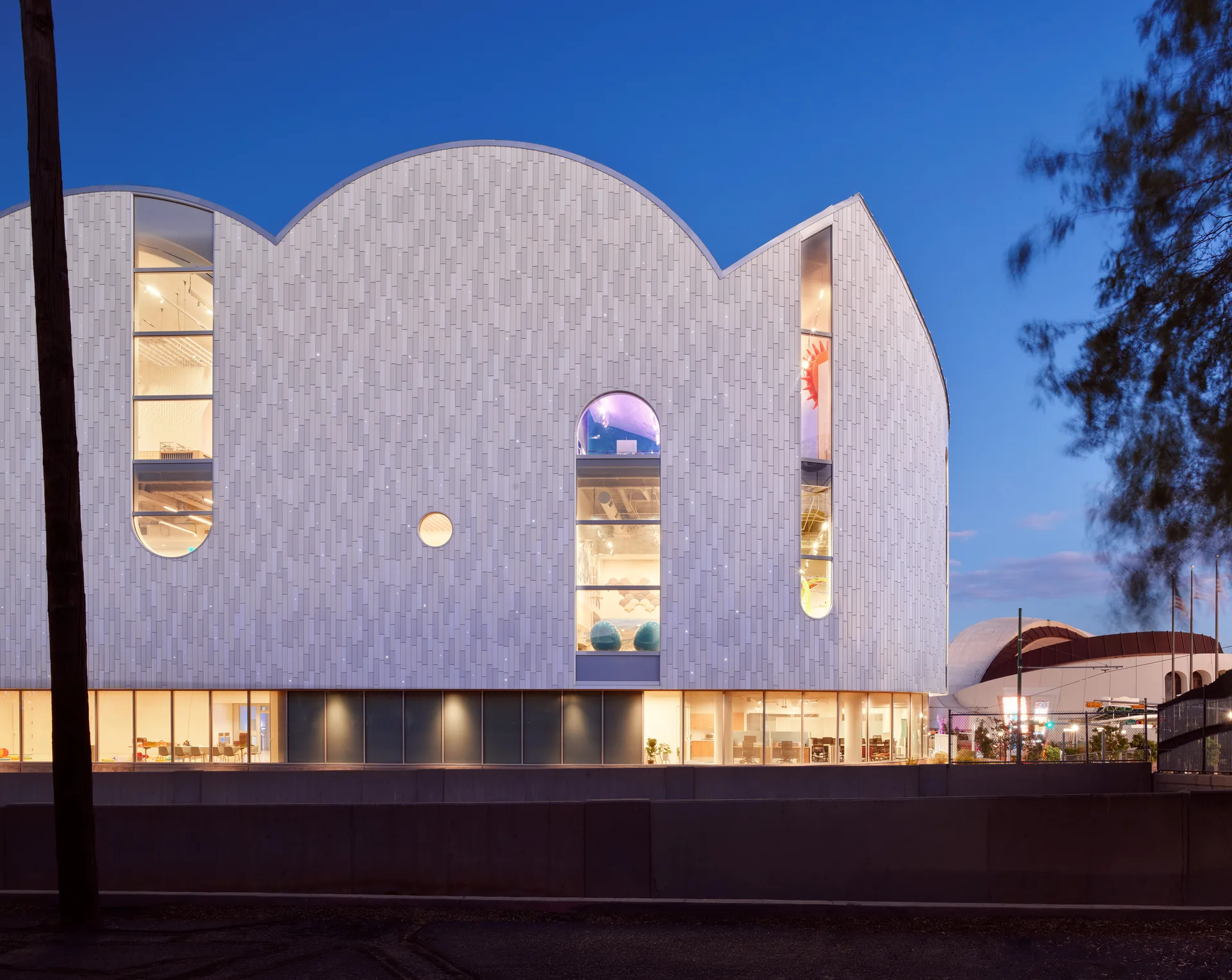 The vaulted facade at dusk with the lit ground floor below