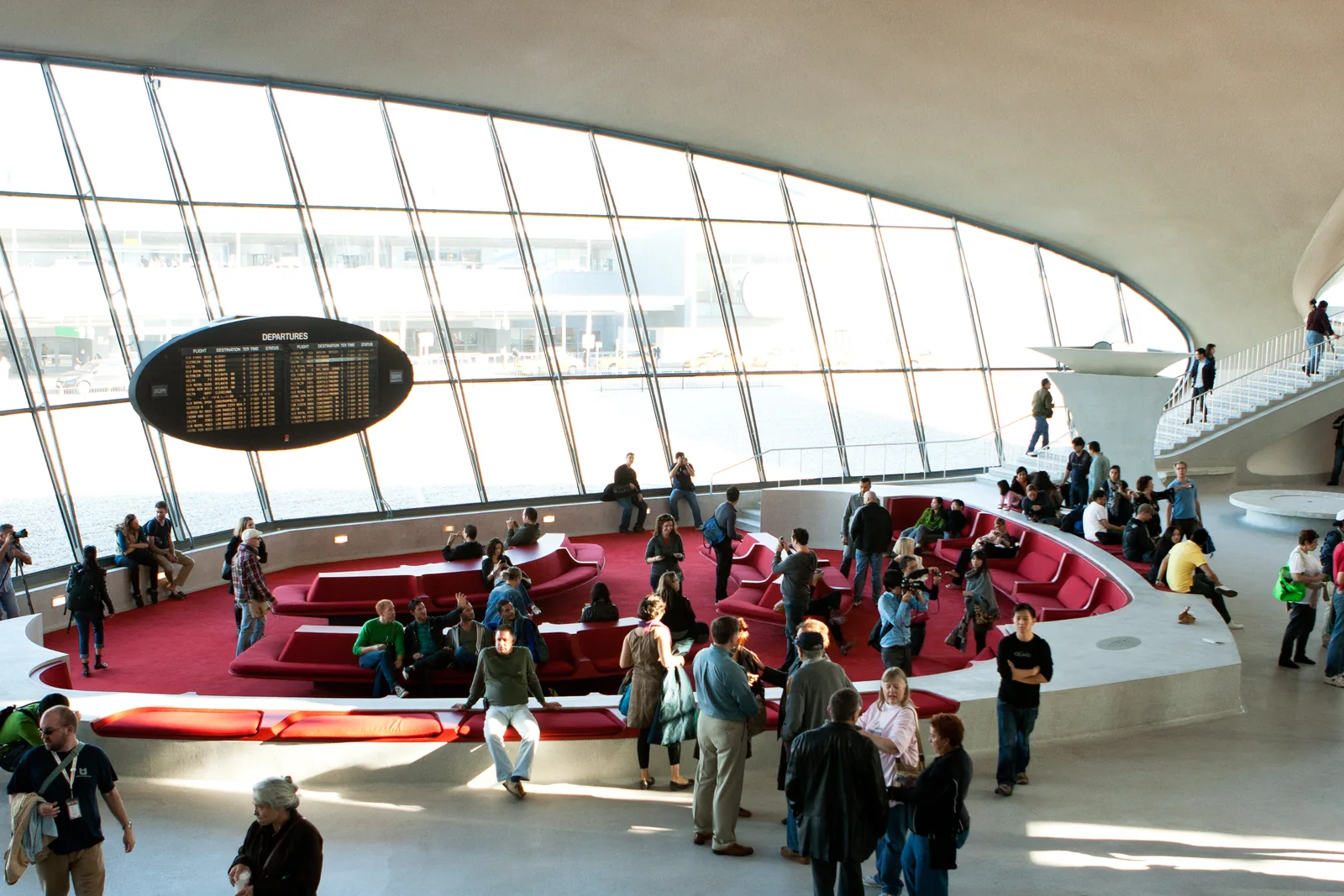 The sunken red lounge of the TWA Flight Center at JFK Airport facing the runway windows under Eero Saarinen's concrete shell