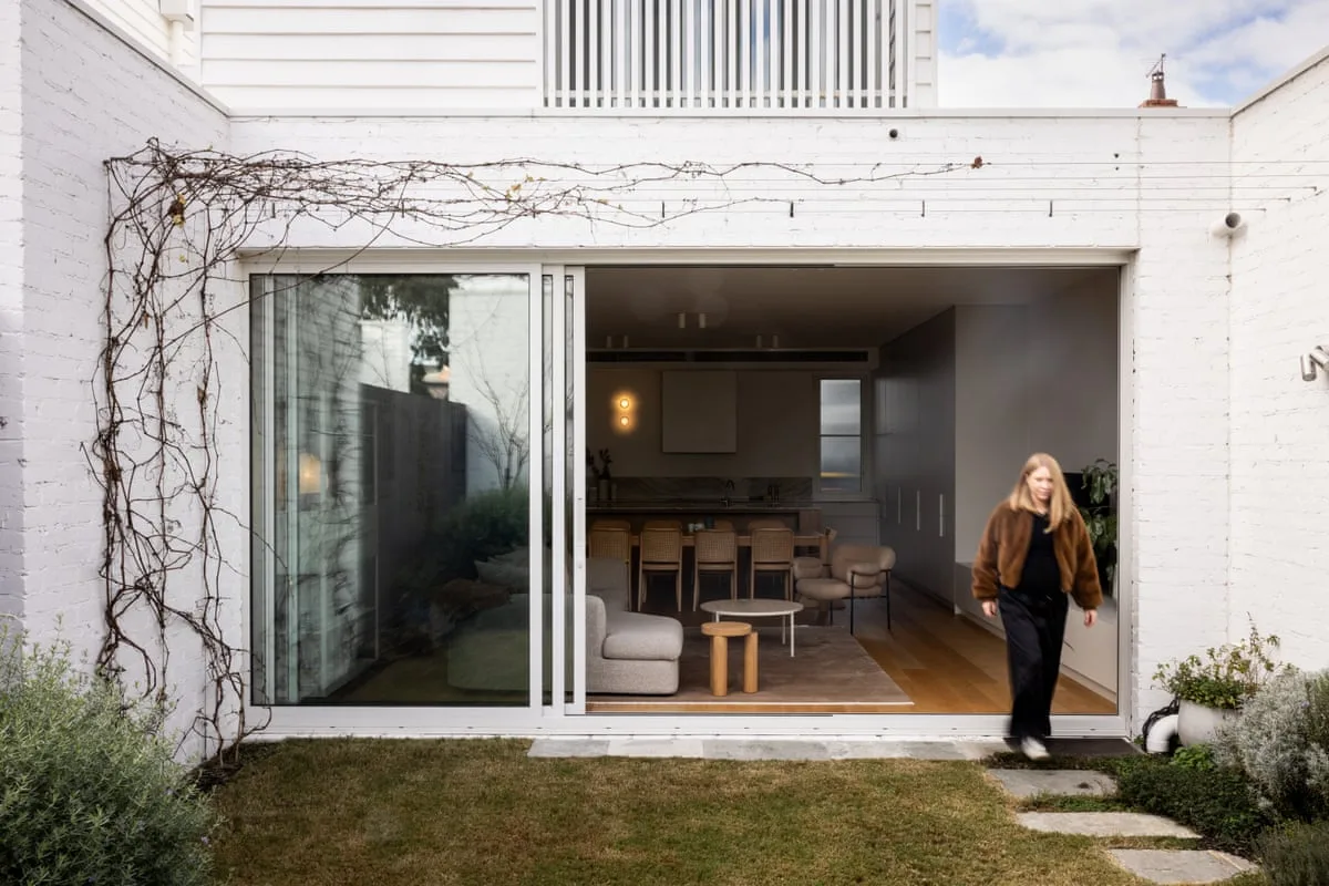 View from a back courtyard into a townhouse living area through an open sliding door