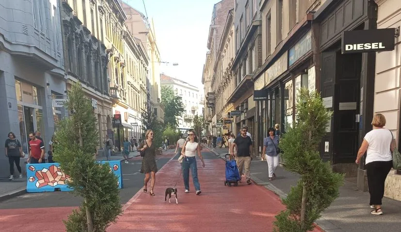 Pedestrians walking on a red path beside storefronts in Zagreb
