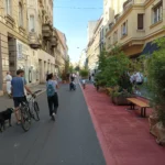 Street scene with pedestrians, cyclists, and greenery on a central road