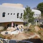 Redhill Early Learning Centre by Hubo Studio, white walls and round windows above the play landscape