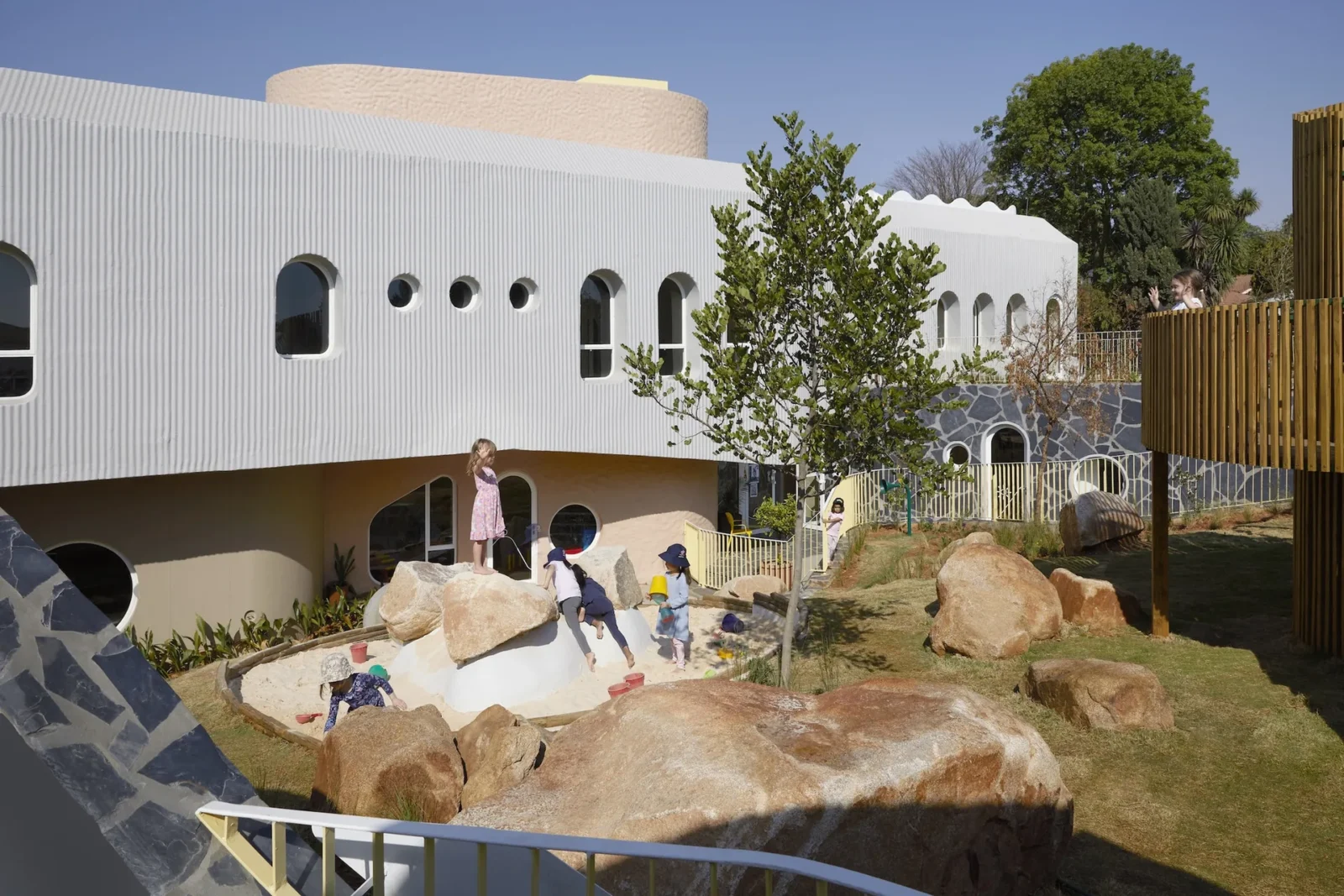 Redhill Early Learning Centre by Hubo Studio, white walls and round windows above the play landscape