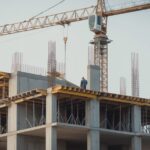 Construction site with a concrete frame rising and several trades working at once