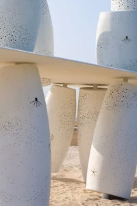 Close view of tilted cylinders pierced with small holes and an octopus shaped opening, Seaside Swing Installation by XBTW OFFICE