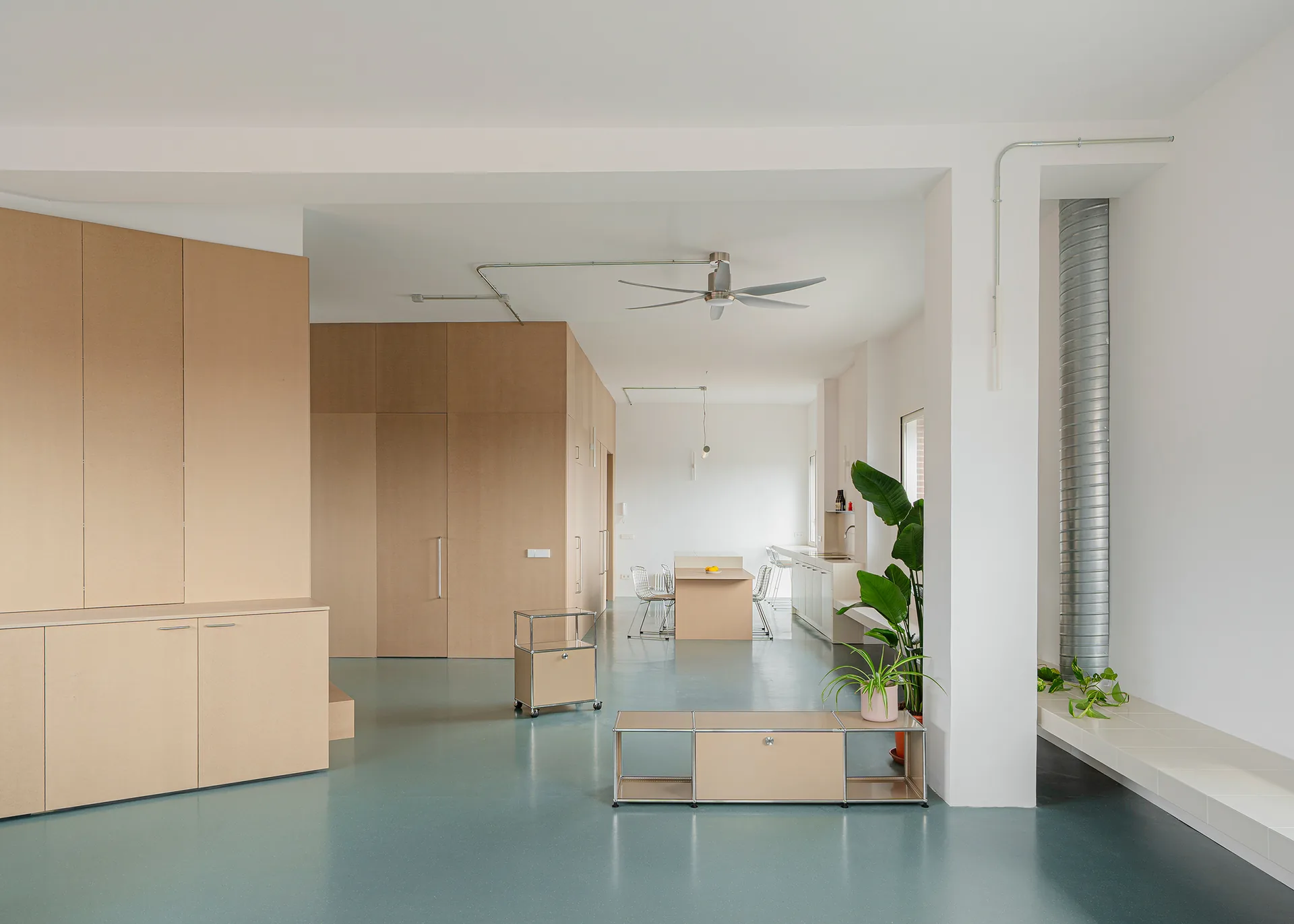 Long view past wooden cabinets and a central timber box toward the windows at the far end, Aguacate Space by ALE Estudio