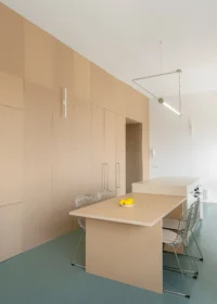 Timber dining table and wire chairs below a linear pendant light beside full height MDF doors, Aguacate Space by ALE Estudio