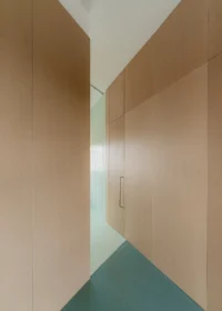 Narrow angled passage between two tall wooden walls where the floor changes from rubber to tile, Aguacate Space by ALE Estudio