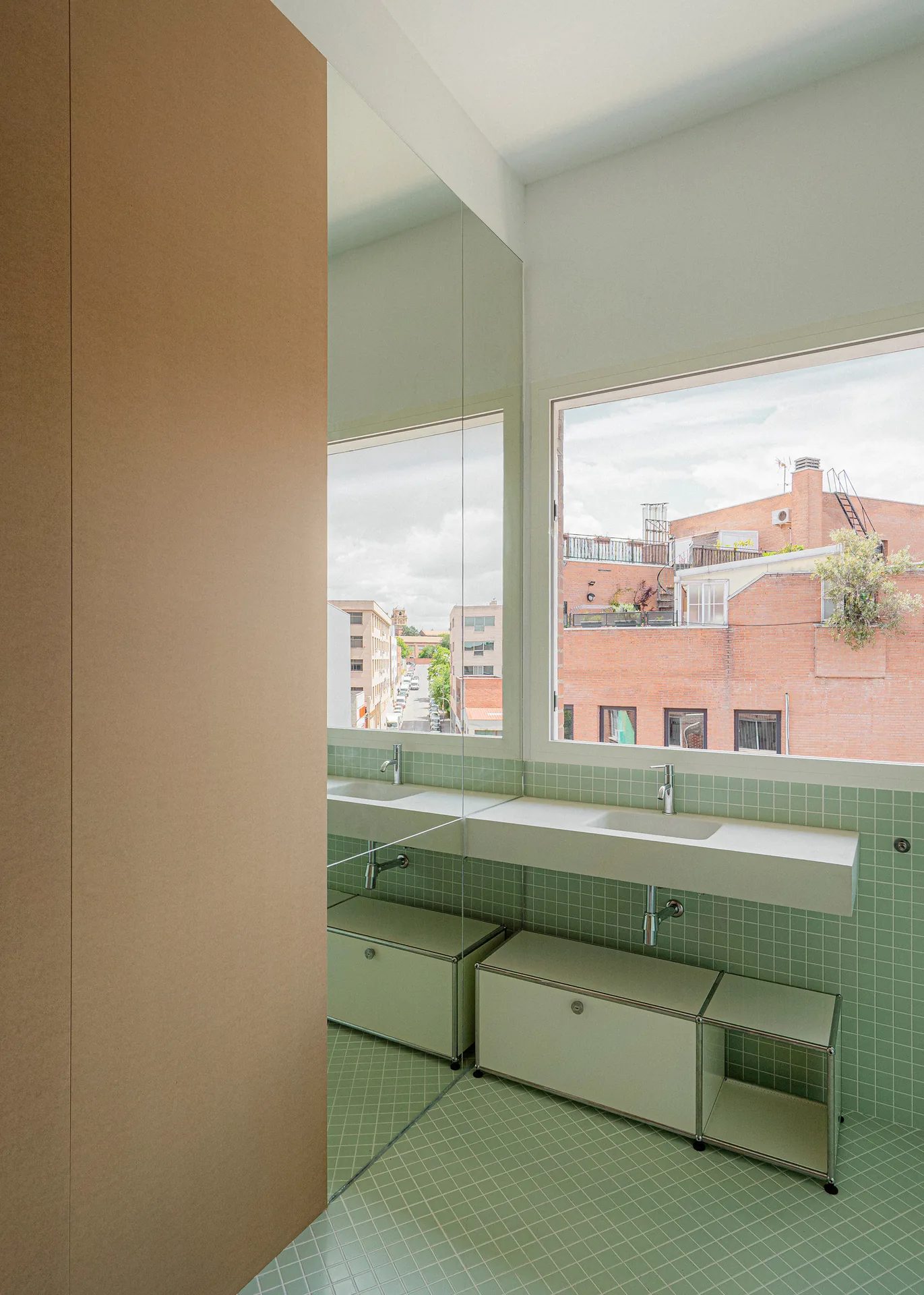 Double basin counter facing large windows with views of brick buildings in Carabanchel, Aguacate Space by ALE Estudio