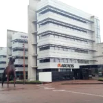 Modern white office building with the Arcadis logo above the entrance and a horse sculpture in front