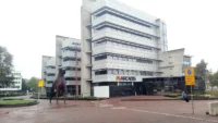 Modern white office building with the Arcadis logo above the entrance and a horse sculpture in front