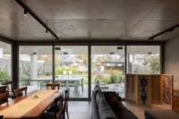 Living and dining room with a long timber table and floor to ceiling glazing onto the courtyard