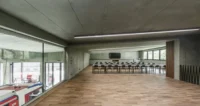 Upper floor lecture room with a timber floor and a large window looking down into the vehicle bay, Civil Protection Centre by Roland Baldi Architects