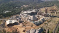 Aerial view of Fortera's Redding ReCarb plant, a cluster of blue silos set within a larger cement works in wooded hills