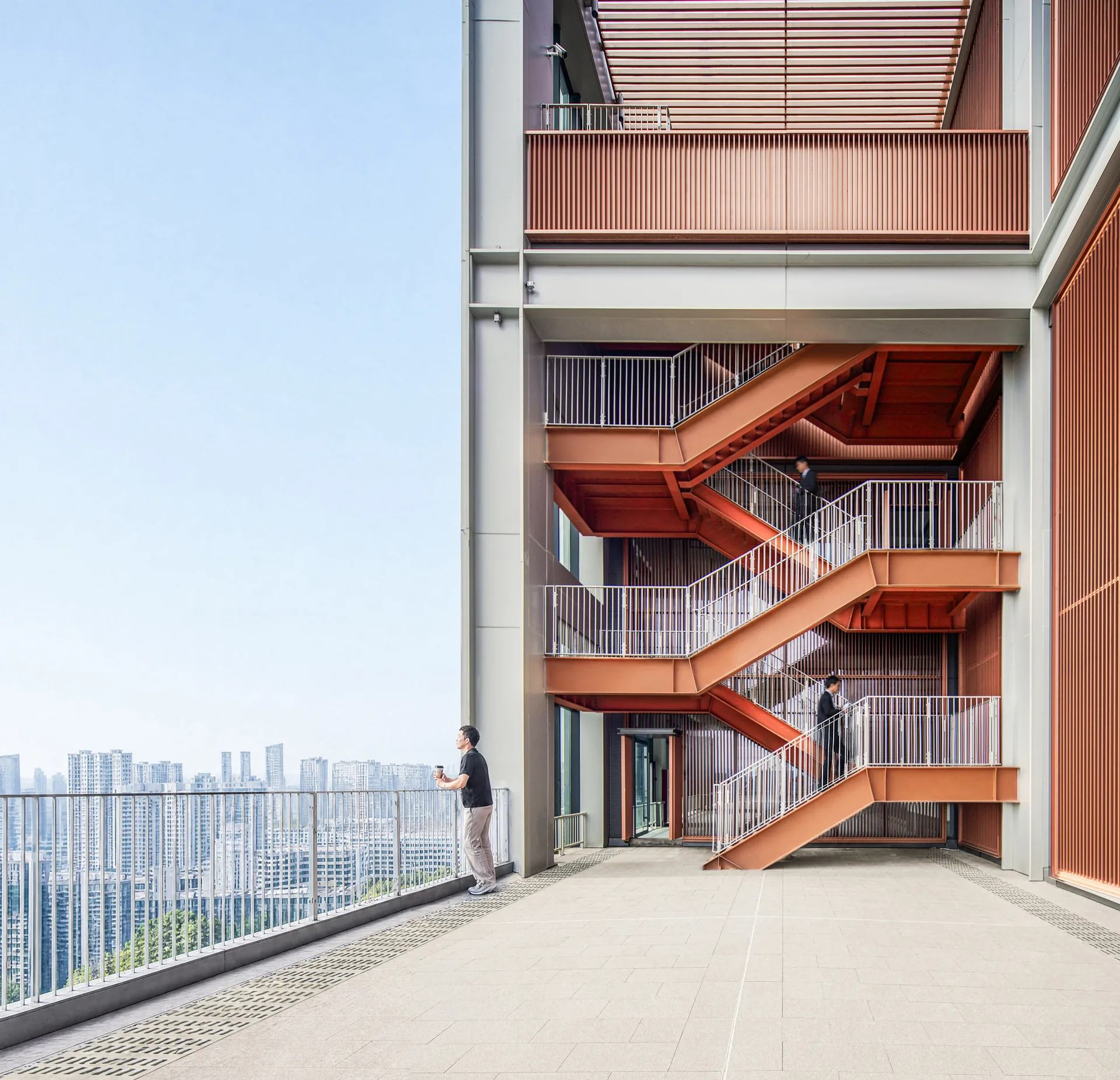 Bronze coloured external stair on a roof terrace with a person looking at the city skyline, Greentown ThinkWorks