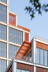 Stepped terraces with bronze canopies on the tower framed by tree branches, Greentown ThinkWorks