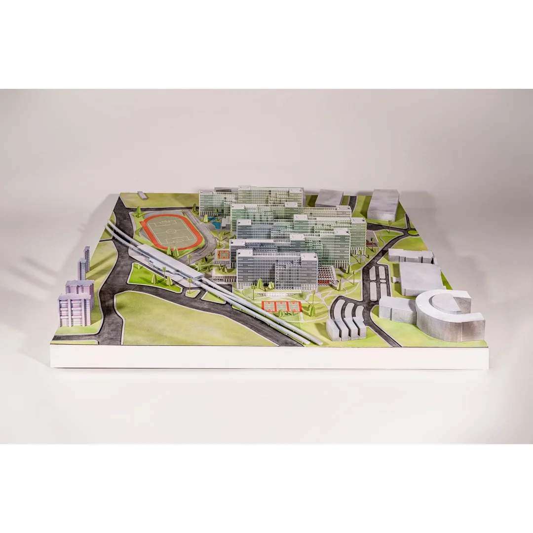 Photo of a white architectural model of a dense hospital campus with an access road, as an urban scale site model
