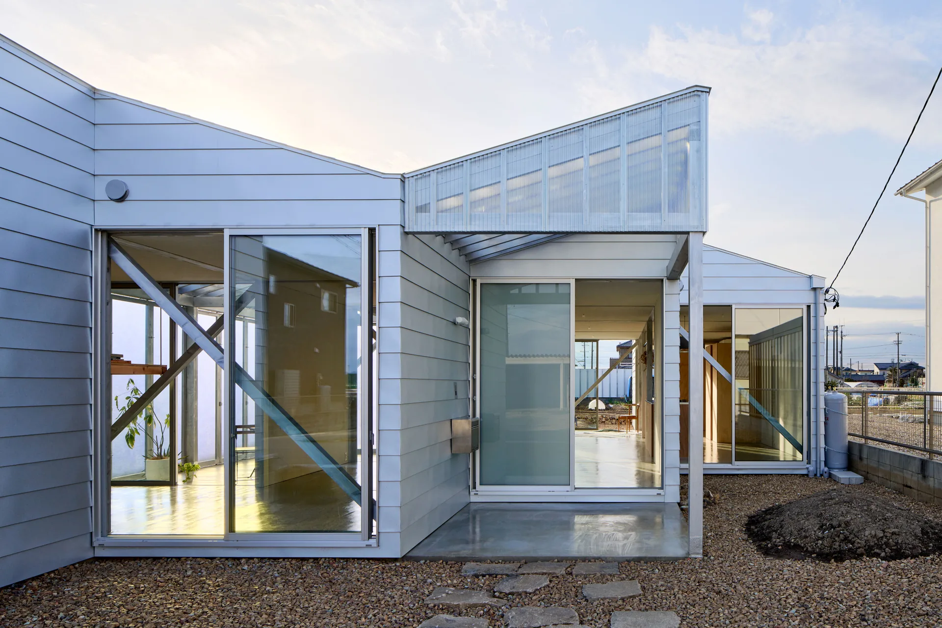 Corner of the house where two gabled volumes meet, with sliding glass doors, diagonal braces and stepping stones, House OY by 1-1 Architects