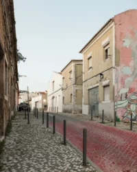 Narrow cobbled street of Vila Maia with older two storey houses and the white converted shed