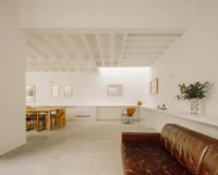 Living area with a brown leather sofa, a long low shelf and a skylight in the joisted ceiling